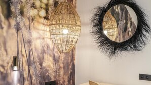 A bedroom with a bed, bedside table, chair, wall art, and a mirror. - Le Bel Abri (Annecy)