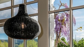 A dining area with a table and chairs, large windows with a view of a pool and greenery, and a hanging light fixture. - Le Bel Abri (Annecy)