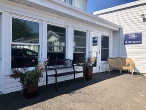 A hotel reception with a bench and potted plants in front.