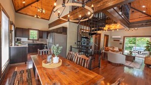 A spacious kitchen with modern appliances, a dining area with a wooden table, and a staircase leading to an upper level.