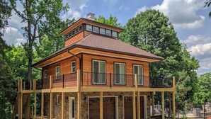 A two-story wooden house with a balcony, a garage, and a stone foundation.