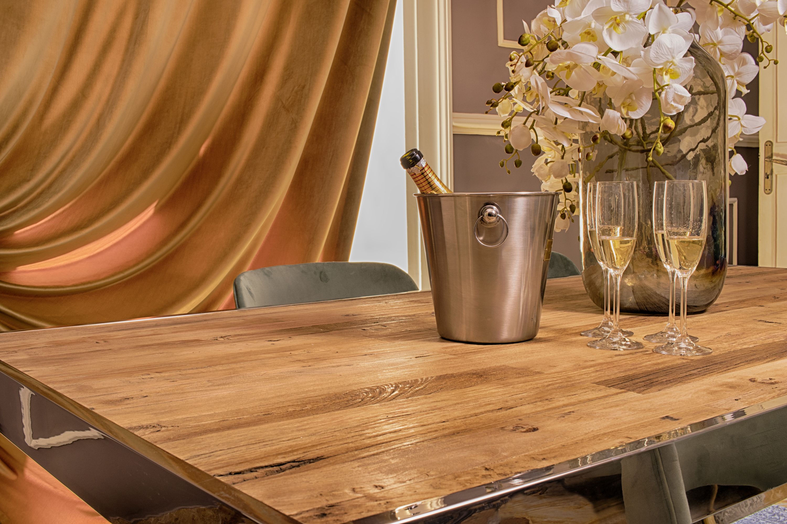 Un tavolo di legno con un secchiello per champagne, due bicchieri e un vaso di fiori bianchi.