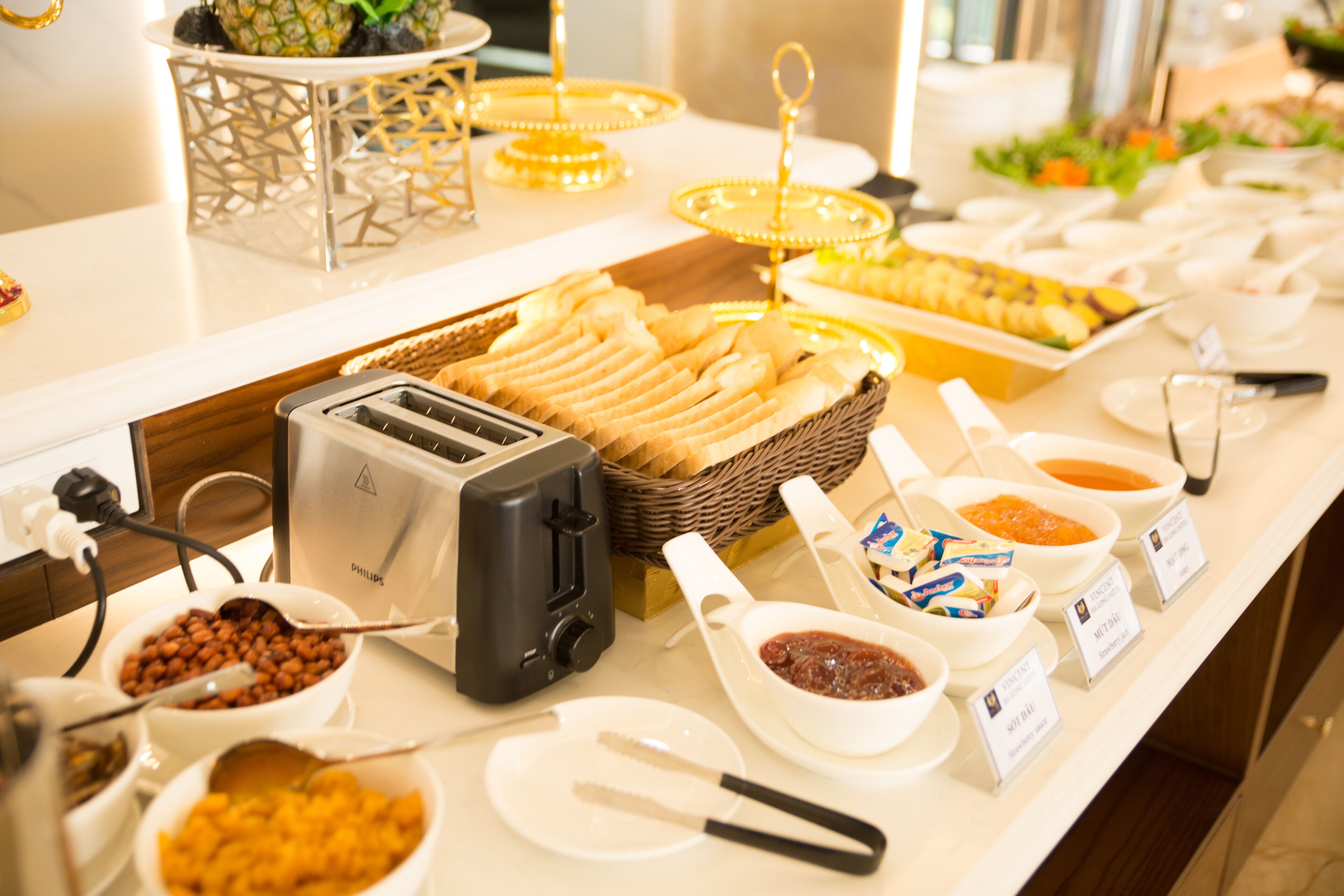A buffet with various food items, including bread, fruits, and condiments.