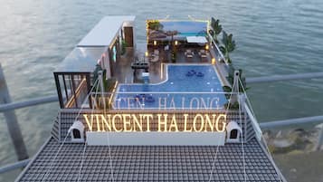 A rooftop pool area with a view of the sea, a lounge with seating, and a sign reading "VINCENT HA LONG".