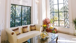 A spacious room with a large sofa, a glass coffee table, and a chandelier. - Vincent Halong Hotel (Bai Chay)