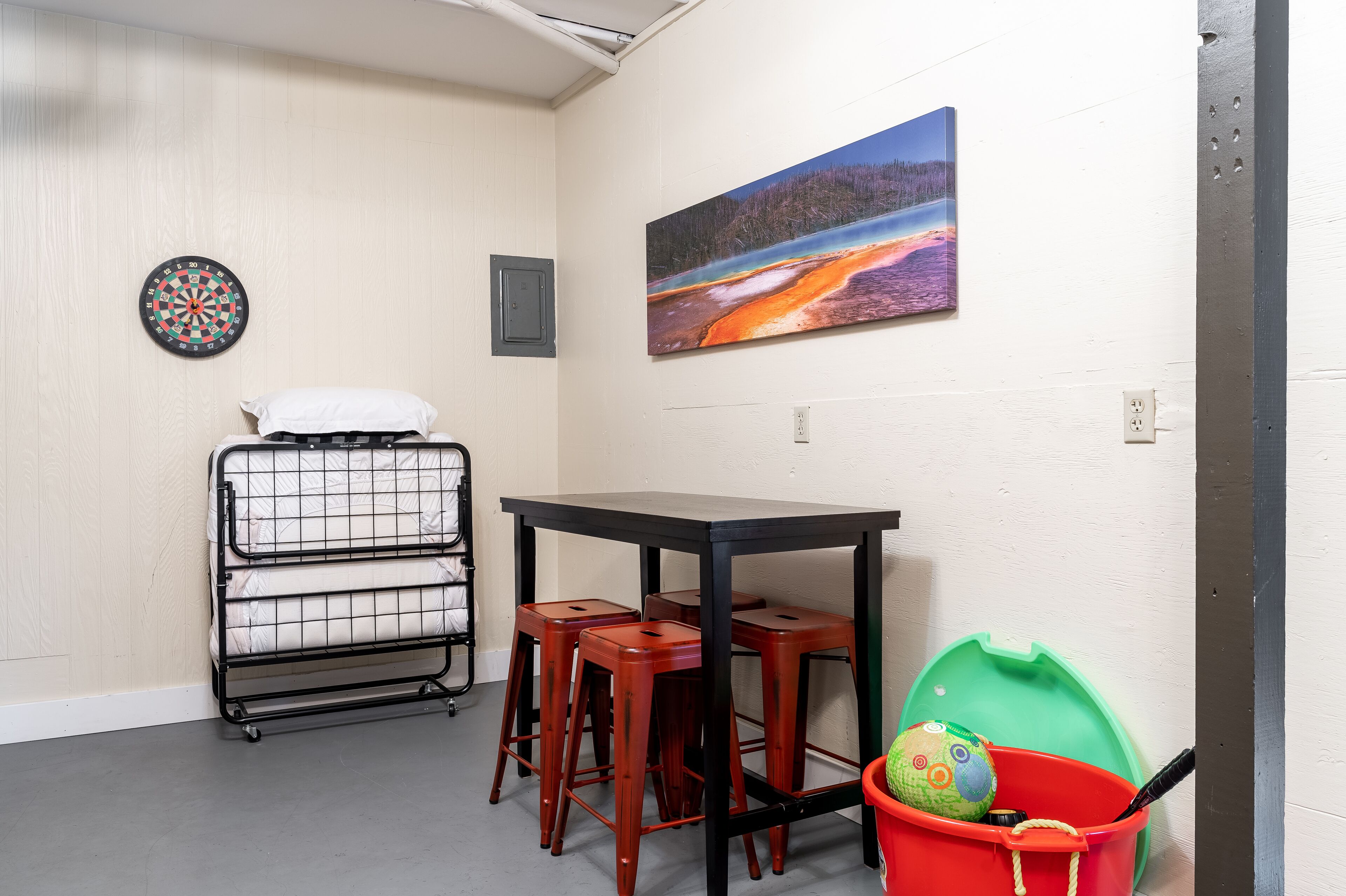 A room with a bunk bed, a small table, and a red bucket.