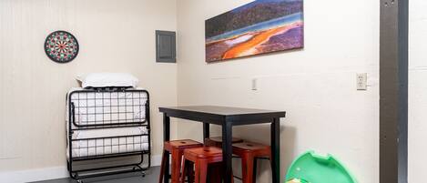 A room with a bunk bed, a small table, and a red bucket.