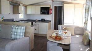 Een compact camperinterieur met een kitchenette, een eethoek en een zithoek.