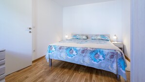 Un dormitorio con cama, mesitas de noche y suelo de madera.