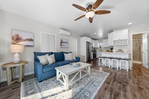 Un salon moderne avec un canapé bleu, une table basse et un ventilateur de plafond.