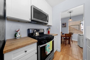 A compact kitchen with a stove, microwave, and a dining area with a table and chairs.