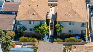 A multi-story residential building with a central staircase, multiple windows, and surrounding greenery. - Ben`s Beach Bungalow 2, 100 Steps to Sand (San Diego)