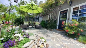 A stone pathway leading to a patio area with outdoor furniture and a green umbrella. - Private Cottage Oasis in CdM - Ideal Village Location on XL Lot (Corona del Mar)