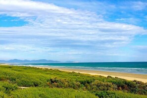 A coastal landscape with a beach, grassy foreground, and distant mountains under a partly cloudy sky. - Prom Coast 2~Getaway to Wilson`s Prom. Walk 2Beach (Sandy Point)