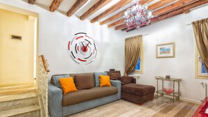A living room with a sofa, a coffee table, a chandelier, and a wall clock. - Venice Dream House Figaro (Venice)