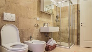 A modern bathroom with a toilet, bidet, sink, and glass-enclosed shower. - Venice Dream House Figaro (Venice)