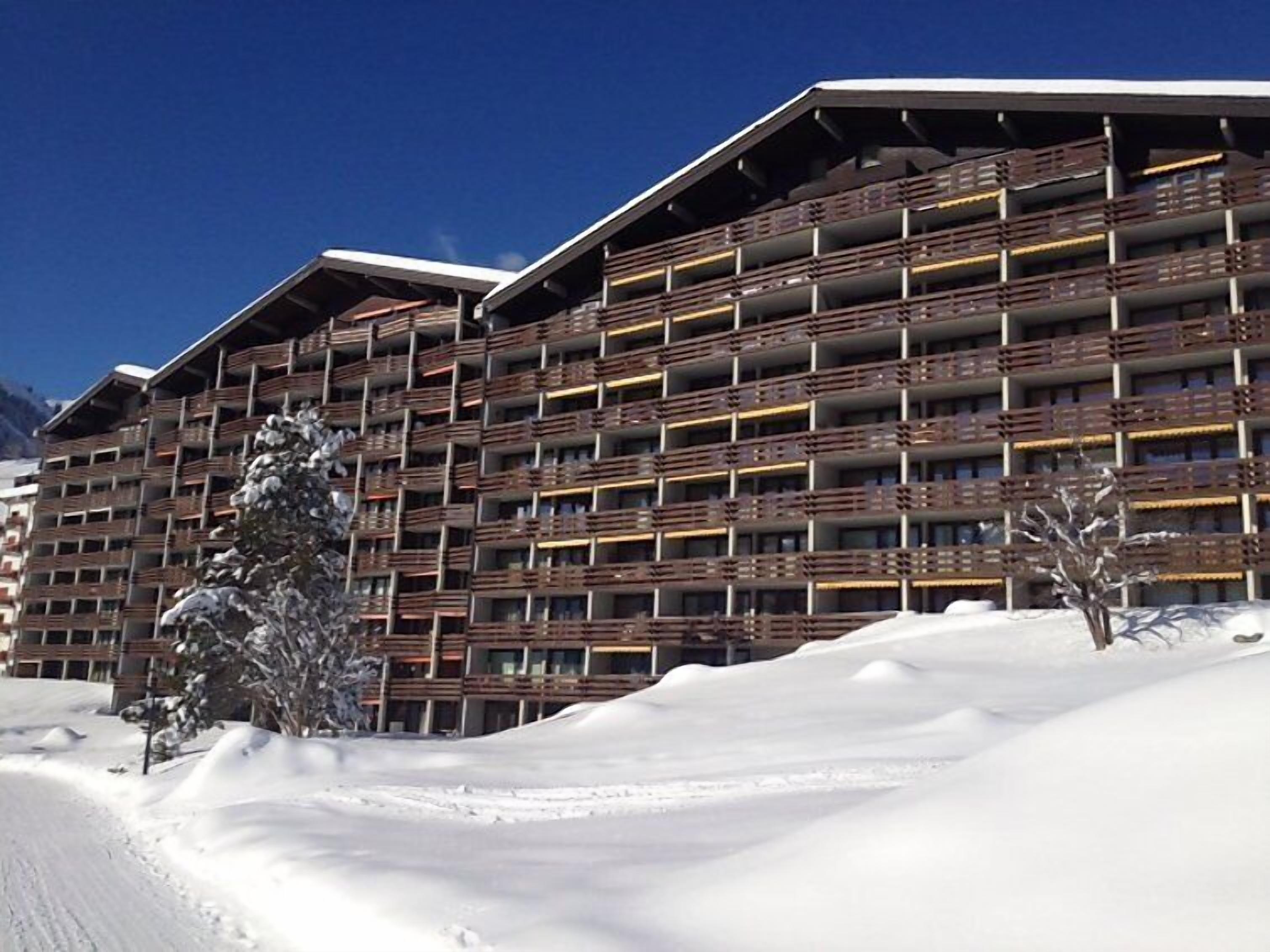 Hotel de diverses plantes amb balcons, envoltat de neu.