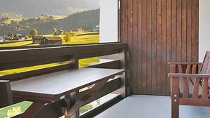 Un balcon avec un banc en bois et une vue sur un paysage montagneux.