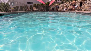 Una piscina cristalina con borde de azulejos, rodeada de sillones de playa y sombrillas.