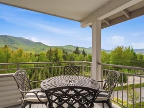 A balcony with a table and chairs, overlooking a mountainous landscape. - Park Pointe A302 - Community Pool/Hot tub! (Chelan)