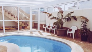 A swimming pool with a curved edge, surrounded by potted plants and white chairs. - Aloe Vera Shared House - Hostel (Granadilla de Abona)