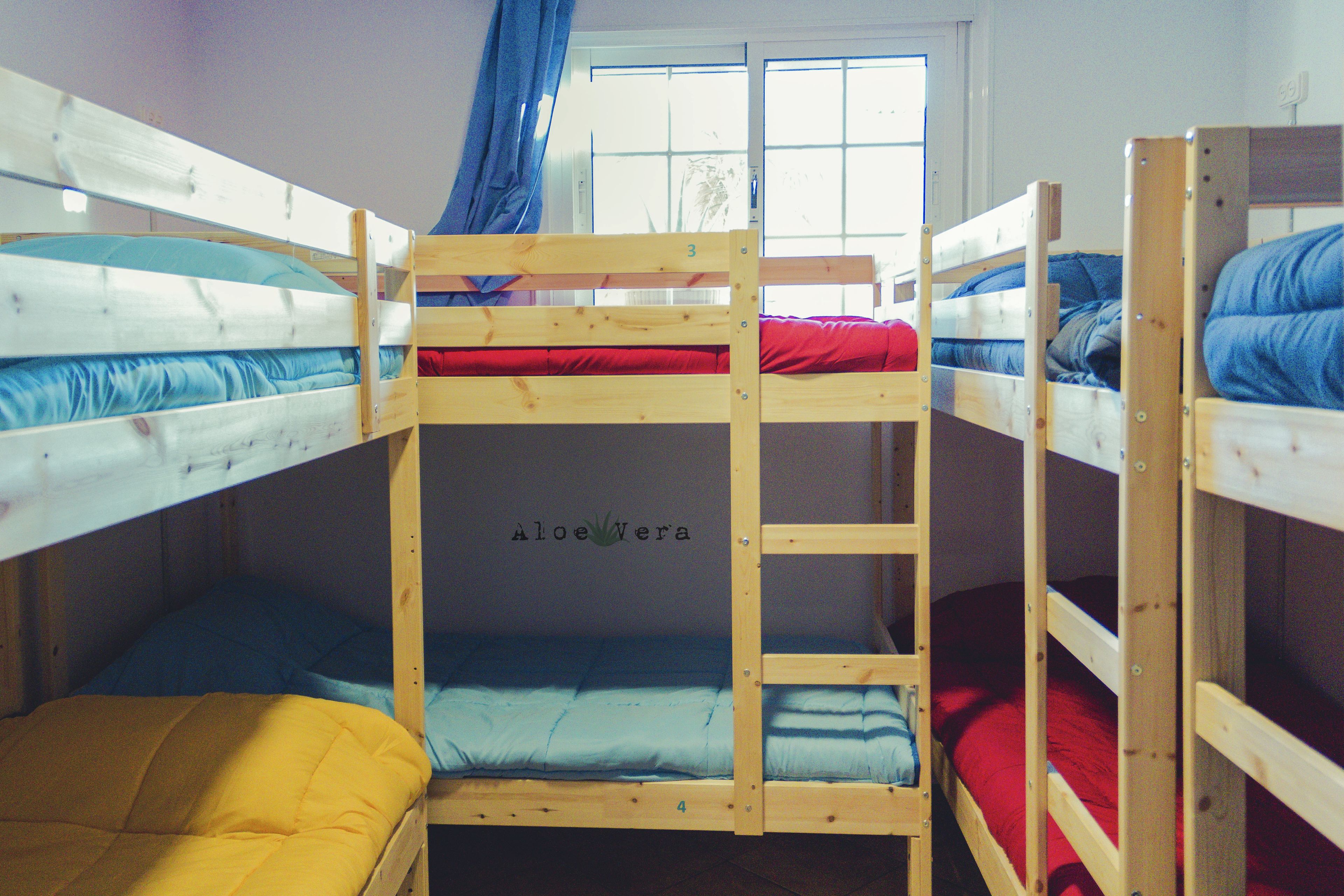 A bunk bed room with three levels, each with a different colored mattress.