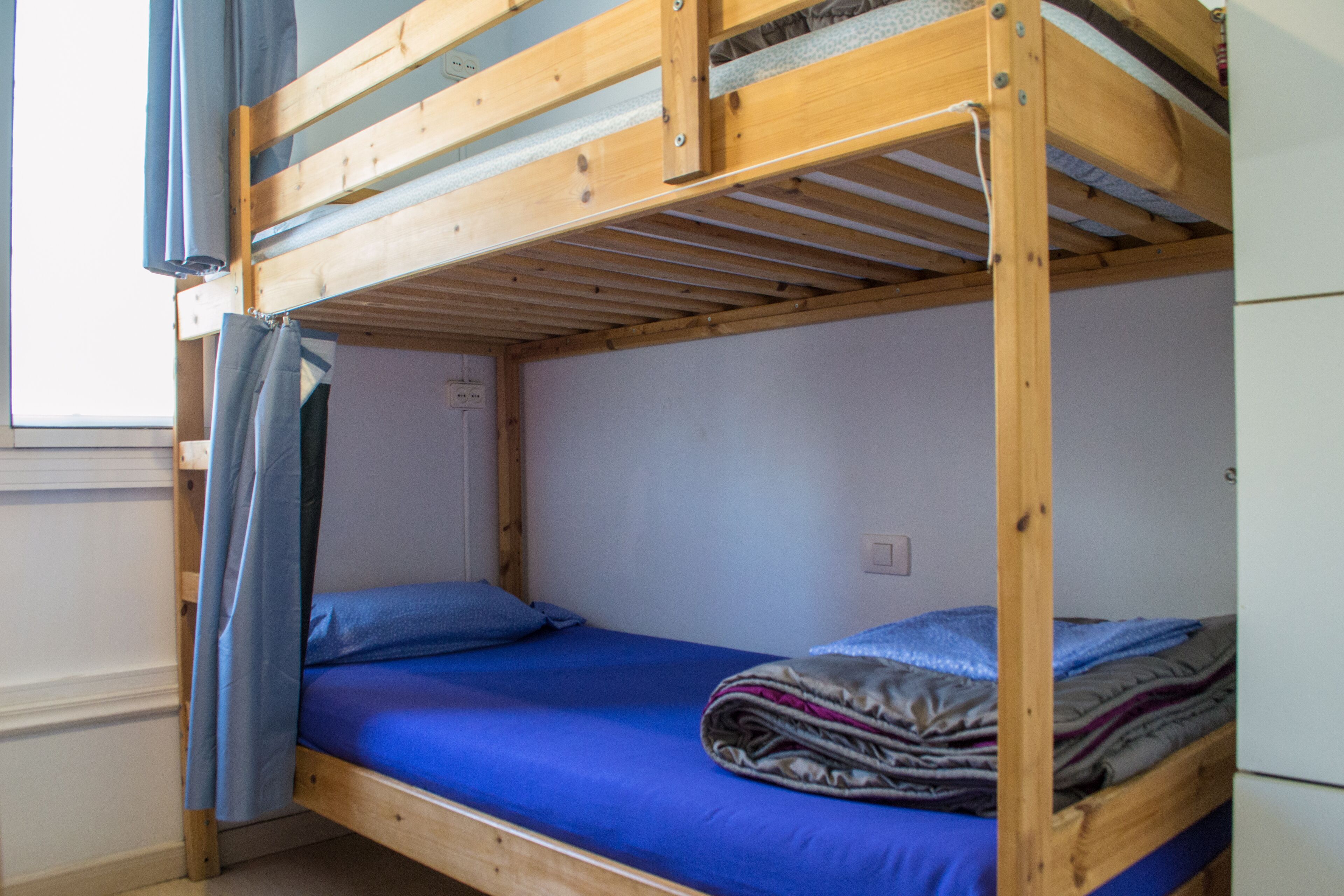 A bunk bed with a blue mattress and a blanket.