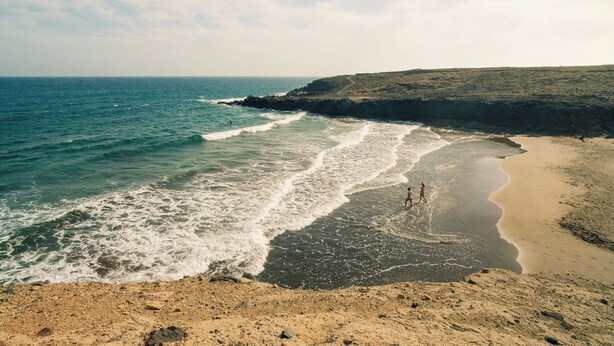 A beach with waves, a sandy shore, and a rocky cliff. - Aloe Vera Shared House - Hostel (Granadilla de Abona)