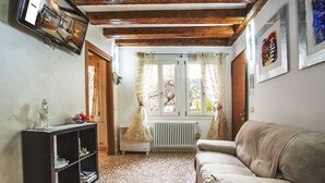 A cozy living room with a sofa, a bookshelf, and a window with curtains.