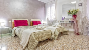 A bedroom with two beds, a vanity with a mirror, and a floral-patterned floor.