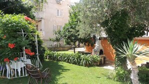 Ein gepflegter Garten mit weißem Zaun, einem Schaukelstuhl und verschiedenen Pflanzen.