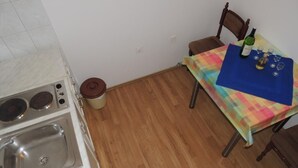 Eine kleine Küche mit Spüle, Herd und einem Tisch mit bunten Tischdecken.