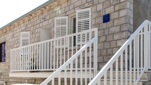 Un escalier avec des rampes blanches menant à un balcon doté de volets.