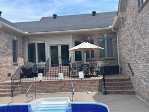 A covered patio area with a pool, outdoor seating, and a brick wall.