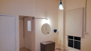 Un dormitorio con cama, cómoda, silla, espejo y ventana.