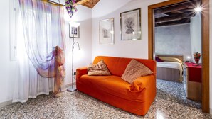 Una stanza con un divano rosso, un letto, uno specchio e opere d'arte alle pareti.