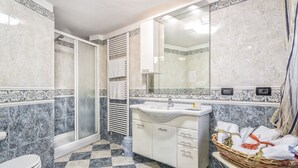 Un bagno con pavimento a scacchi, un lavandino, uno specchio e un box doccia.