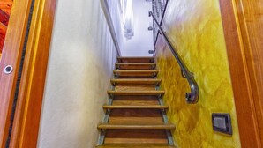 Una scala in legno con corrimano e interruttore a muro.