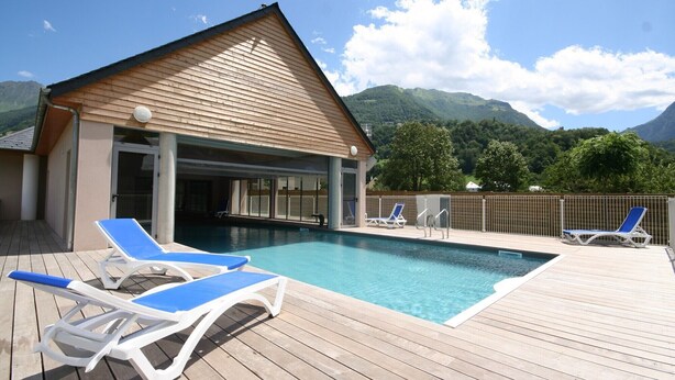 A pool area with two lounge chairs and a building with a sloped roof. - Residence Val de Roland - Studio Apartment 2 persons (Luz-Saint-Sauveur)