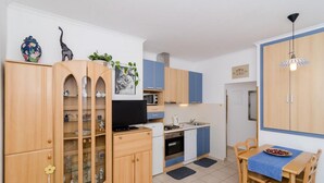 Eine kompakte Küche mit Holzschränken, einer eingebauten Mikrowelle und einem Essbereich mit Tisch und Stühlen.