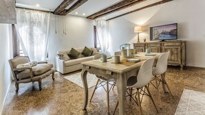 Un salon comprenant une table à manger en bois, des chaises, un canapé et un téléviseur.