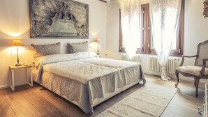 Une chambre à coucher avec un grand lit, deux tables de chevet avec des lampes, une chaise et un radiateur.
