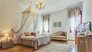 Une chambre à coucher avec un lit à baldaquin, un canapé, un bureau et un téléviseur.