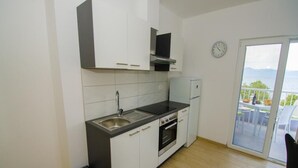 A modern kitchen with a built-in oven, a sink, and a window overlooking a balcony. - Apartments Vesela - Comfort One Bedroom Apartment with Balcony and Sea View (Janjina)