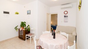 Un coin repas avec une table ronde, des chaises, une plante en pot et un canapé.