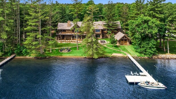 Un chalet au bord du lac, doté d’un quai, d’un bateau et d’une pelouse bien entretenue.