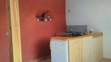 Een koelkast, een kookplaat, kookgerei, borden en bestek