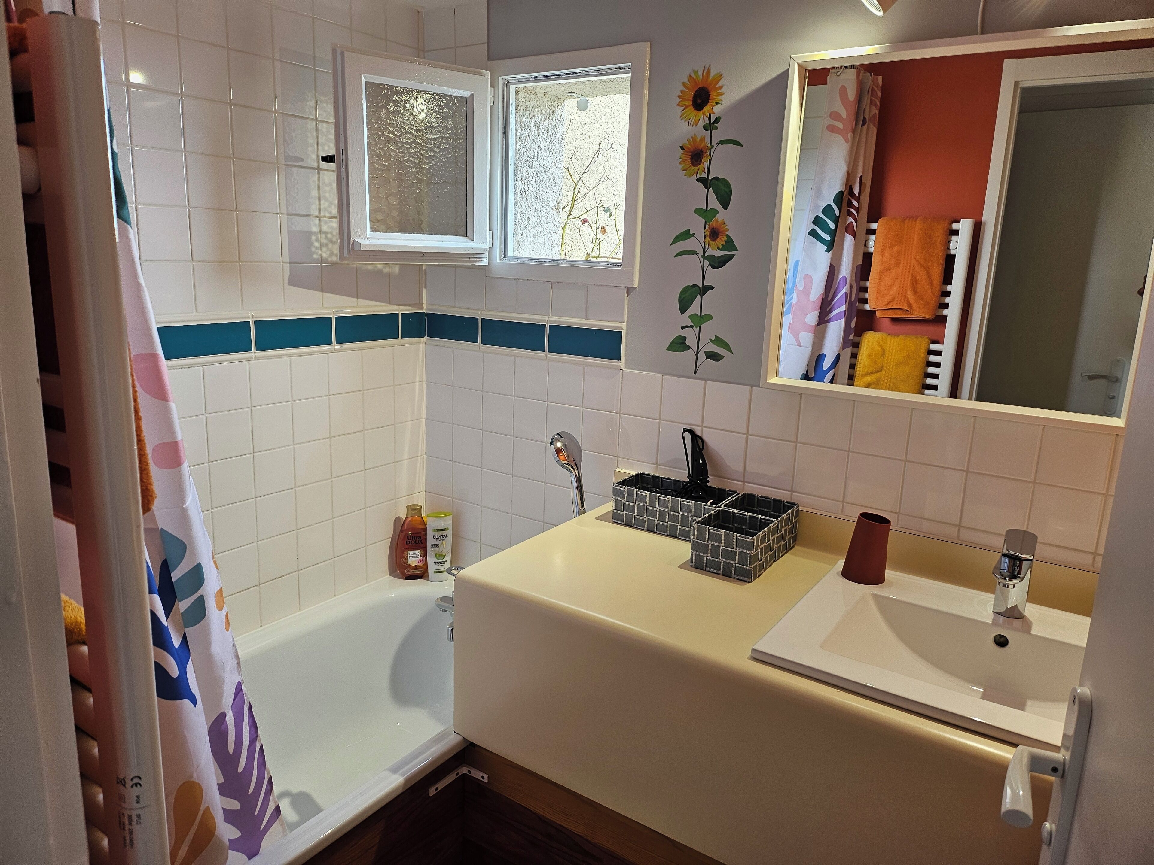 Une salle de bain avec une baignoire, un lavabo, un miroir et une fenêtre.