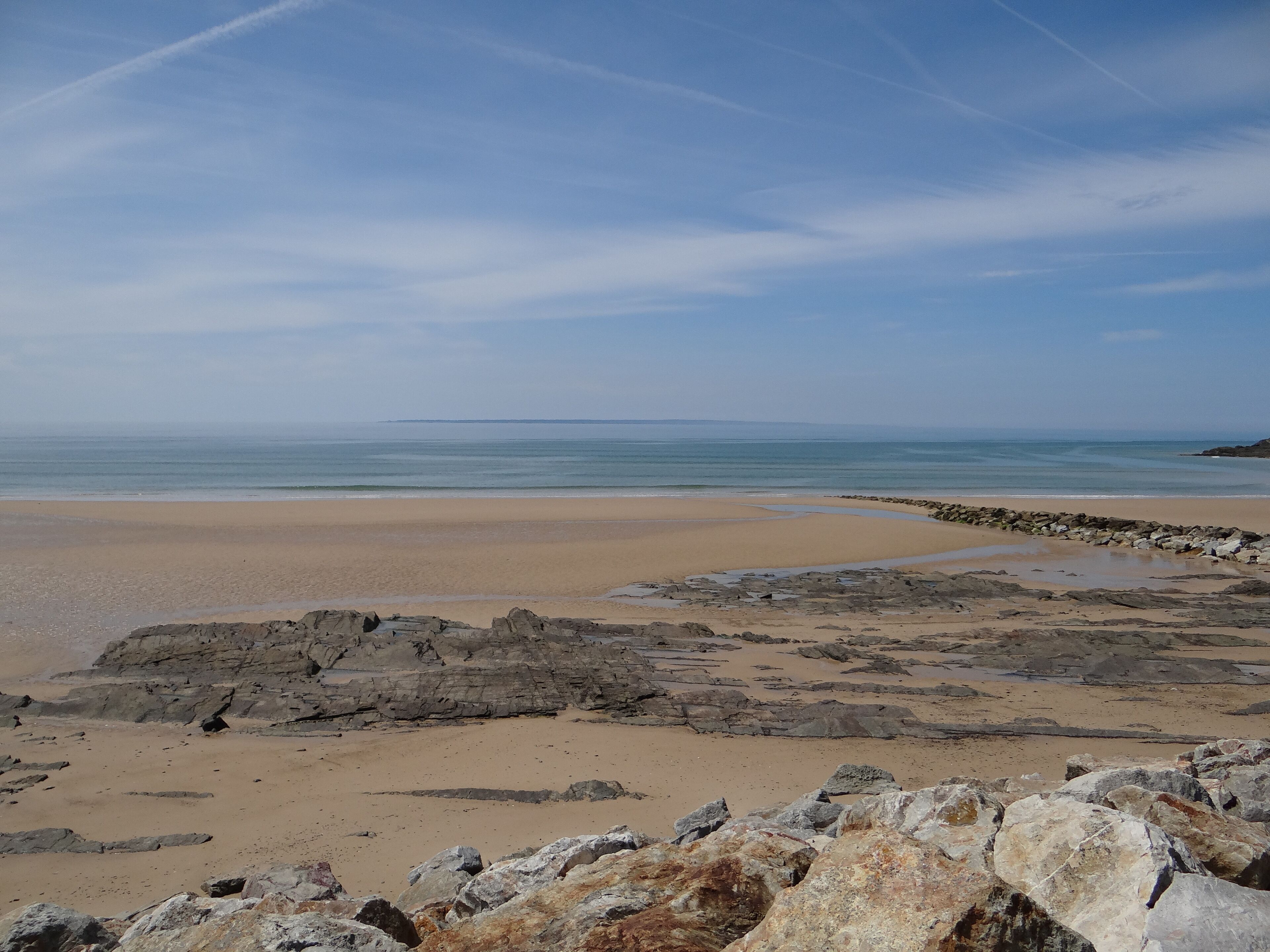 A beach with rocky terrain and a clear sky.