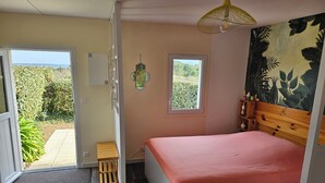 A bedroom with a bed, a wooden headboard, a window, and a view of greenery outside.